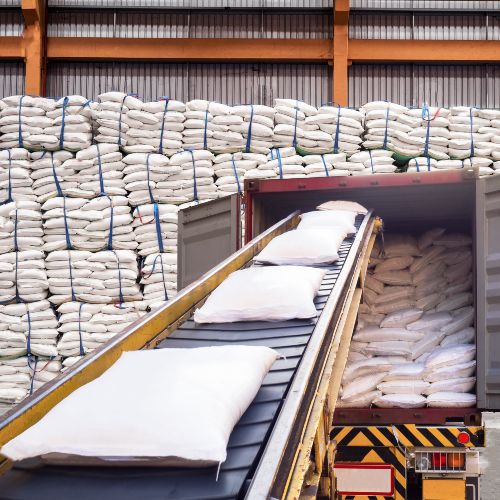 photo of the interior os a sugar factory with bags of sugar going down a conveyor belt