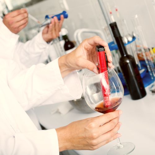scientists in white lab coats adding chemicals and additives to wine