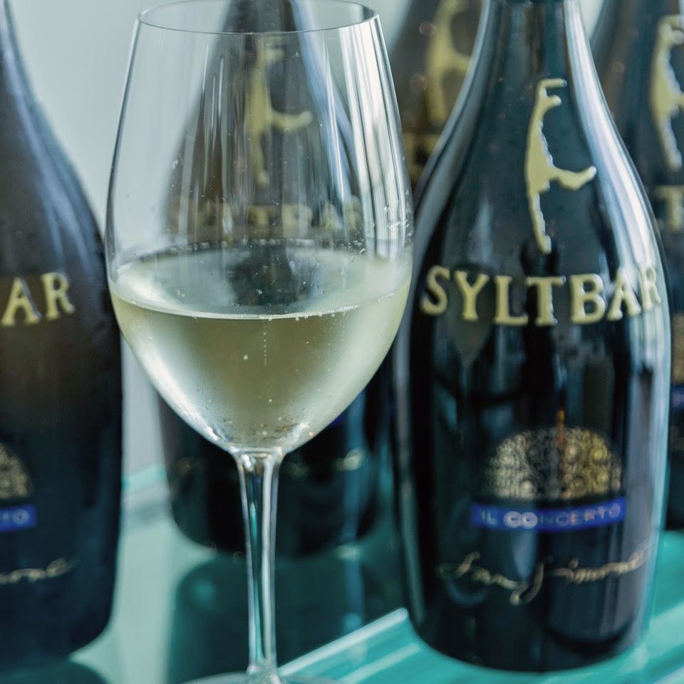 photo of a chilled glass of Mr SYLTBAR low-sugar premium prosecco in front of several bottles of Mr