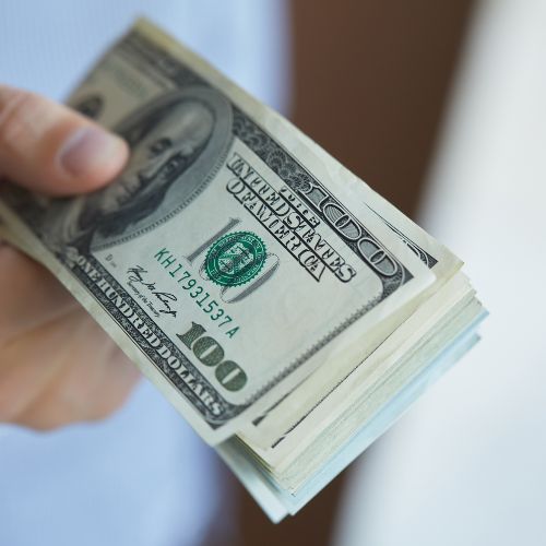 photo of a hand holding a stack of $100 dollar bills