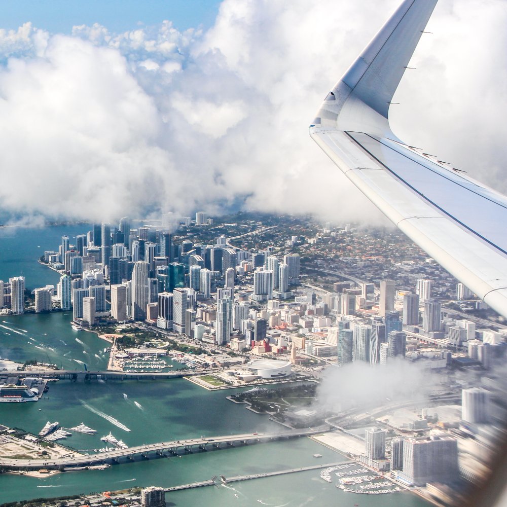 photo of Miami Florida from the inside of a plane with plane wing in photo